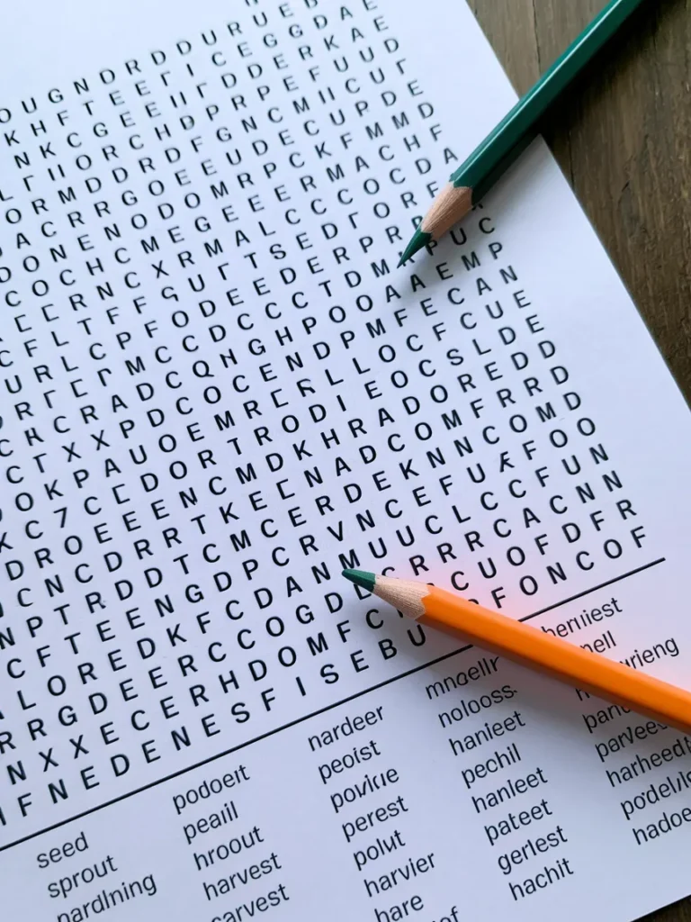 A close-up of a printed word search puzzle sheet with gardening-related words like seed, sprout, soil, and harvest circled in colored pencil.