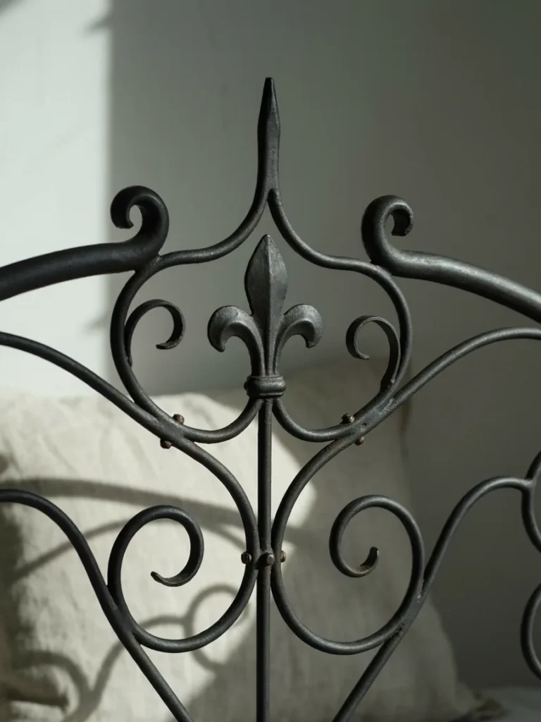 A detail shot of ornate iron scrollwork on a headboard