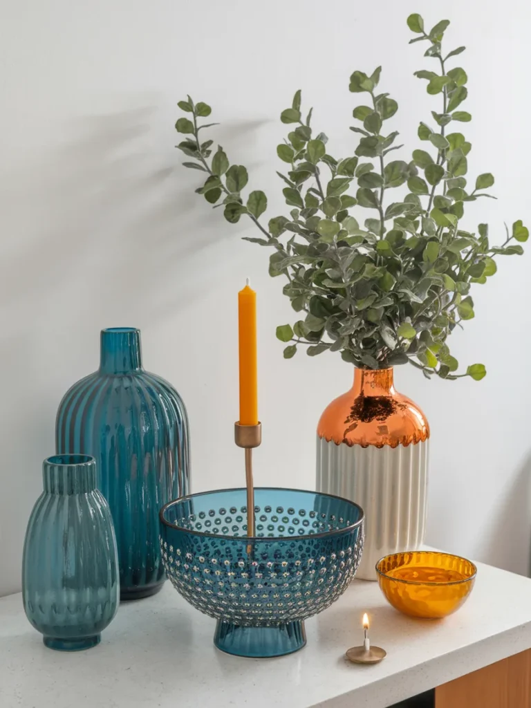 Accessories for blue and orange living room decor including vase, glass bowl, candles, and plant