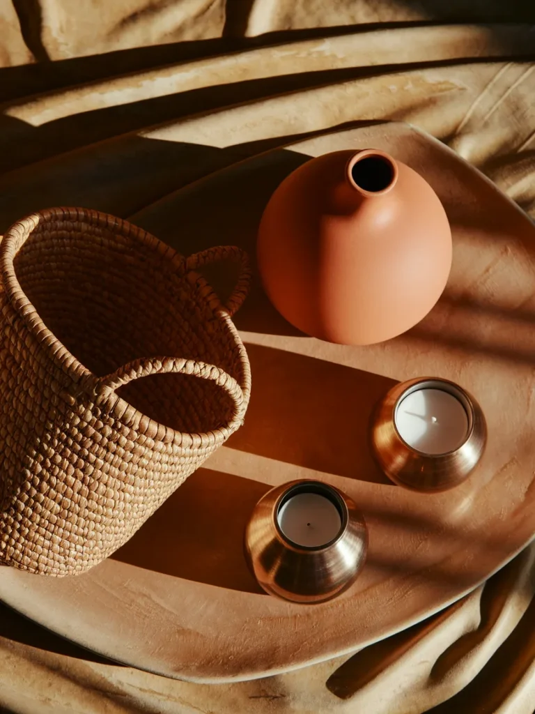 Close up flat lay of mixed textures, such as a woven basket, a smooth ceramic vase, and a metal candle holder, grouped together to show material contrast
