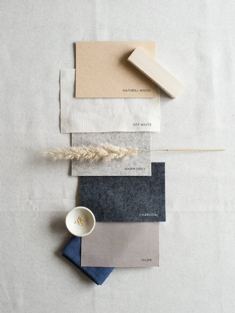 Flat lay of natural wood tone, off white, warm grey, and charcoal color swatches arranged on a neutral surface, restrained Japanese inspired bedroom decor color palette